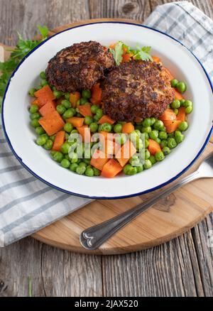 Pois et carottes avec boulettes de viande de porc sur une assiette. Servi sur fond de table rustique et en bois avec espace pour les copies Banque D'Images