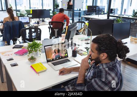 Homme d'affaires biracial travaillant avec une collègue biracial lors d'un appel vidéo au bureau. Non modifié, affaires, technologie sans fil, appel vidéo, réunion, bt Banque D'Images