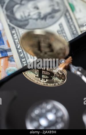 Bitcoin réfléchissant sur le plateau du disque dur. Crypto-monnaie numérique sur disque dur et billets en dollars en arrière-plan. L'extraction de crypto et le coût de la minin Banque D'Images