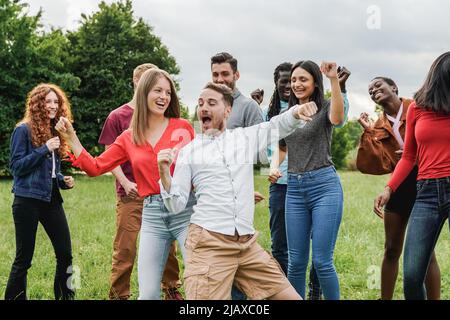 Groupe multiethnique d'amis qui dansent ensemble en plein air pendant les vacances d'été - Focus sur le visage de l'homme central Banque D'Images