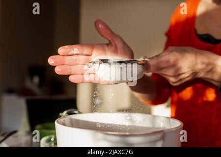 Les mains arrosées de poudre dans le bol. Banque D'Images