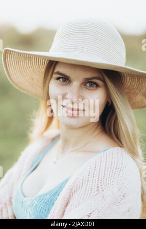 une femme en veste et chapeau profite du coucher de soleil seul Banque D'Images