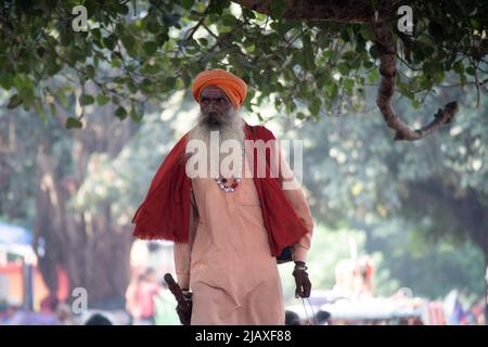 Sadhu monk portant les robes de safran saints à l'hindouisme et un sac avec des symboles saints tout en marchant parmi les gens sur les rives du fleuve sacré ganga Banque D'Images