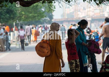 Sadhu monk portant les robes de safran saints à l'hindouisme et un sac avec des symboles saints tout en marchant parmi les gens sur les rives du fleuve sacré ganga Banque D'Images