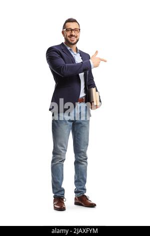 Portrait complet d'un jeune homme avec des lunettes tenant des livres et pointant isolé sur fond blanc Banque D'Images