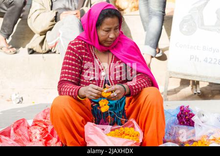 Katmandou, Népal - 17 novembre 2018: Femme vendeur vendant des fleurs de marigold pour des couronnes sur le marché de rue Banque D'Images