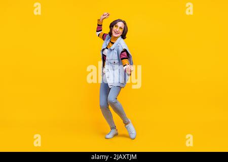 Pleine photo de hipster blanc coiffure dame aînée danse vêtements de lunetterie chandail jeans chaussures isolées sur fond jaune couleur Banque D'Images