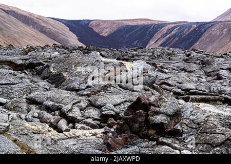 Des plaques de lave solidifiée du volcan Geldingadalir sont empilées sur la péninsule de Reykjanes près de Grindavík, en Islande ; de fines dépôts minéraux jaunâtres se montrent sur la roche grise. La lave date de l'éruption de mars à septembre 2021, la plus récente d'Islande à l'époque. Banque D'Images