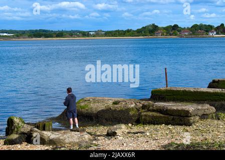 Personne pêchant par l'ancien pont ferroviaire désutilisé connu sous le nom de Billy Line au-dessus du port de Langstone qui reliait l'île Hayling au continent. Banque D'Images