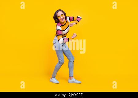 Photo du corps entier de la belle coiffure blanche femme aînée danse porter des lunettes chandail jeans chaussures isolées sur fond jaune couleur Banque D'Images