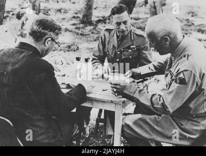 Déjeuner informel pour visiter Monarch sur le front africain -- Afrique du Nord... le roi George d'Angleterre participe à un déjeuner informel, en mangeant une boîte de mess de l'armée américaine, lors de sa visite aux forces américaines certains-où sur le front africain. Sur la gauche se trouve le lieutenant-général Mark Clark, États-Unis; sur la droite se trouve le major-général Patton. Assis avec dos à la caméra se trouve Sir James Grigg, ministre britannique de la guerre, qui a accompagné le roi lors de sa visite aérienne. 04 octobre 1943. (Photo d'Interphoto News Pictures, Inc.). Banque D'Images