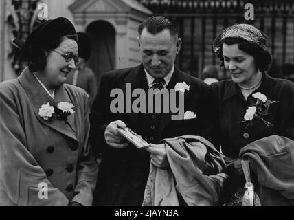 H.M. le Roi tient une investiture -- de gauche à droite M. John Johnston montre sa Médaille George à son épouse (à sa droite) et à Mme Sally Young (soeur en droit). Il a pris un cylindre flamboyant d'une œuvre de Glasgow à l'extérieur du palais aujourd'hui. Le Roi a tenu une investiture au Palais de Buckingham aujourd'hui mardi, où le nouveau chevalier a reçu l'accolade et les décorations pour la bravoure ont été décernées. 4 juillet 1950. (Photo de Fox photos). Banque D'Images