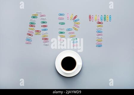 Concept d'art moderne : directement au-dessus de la vue des trombones colorés disposés en forme d'inscription artistique et de tasse à café Banque D'Images