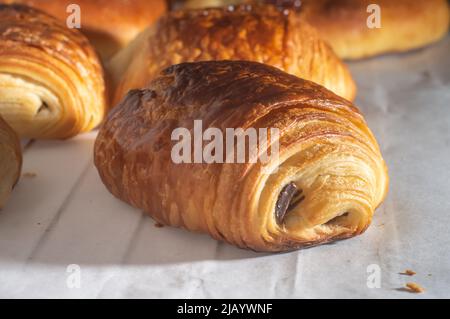 Un croissant au chocolat traditionnel français fraîchement préparé - petit pain au chocolat brillant aux rayons du soleil du matin. Banque D'Images