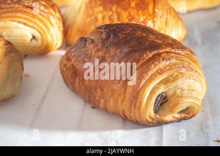 Un croissant au chocolat traditionnel français fraîchement préparé - petit pain au chocolat brillant aux rayons du soleil du matin. Banque D'Images