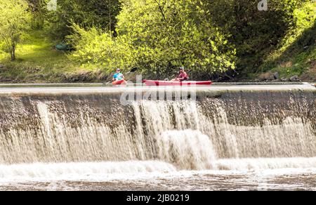 Elora, Ontario, Canada - 05 15 2022 : rameurs en kayaks rouges lumineux à côté des chutes d'eau de la rivière Grand, près de la communauté d'Elora dans le canton de Banque D'Images