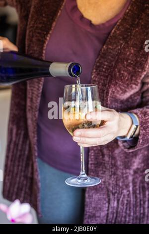 Une femme en hiver verse un verre de vin blanc Banque D'Images