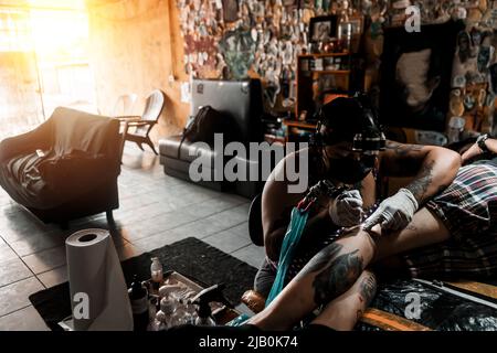 Latina tatouage artiste travaillant sur un art sur la jambe d'un client dans un studio au Nicaragua Banque D'Images