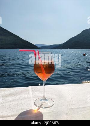 Un cocktail Aperol devant une belle vue estivale avec la mer et les montagnes Banque D'Images