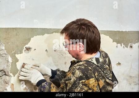 enlever la peinture du mur à l'aide d'un grattoir, réparer la pièce Banque D'Images