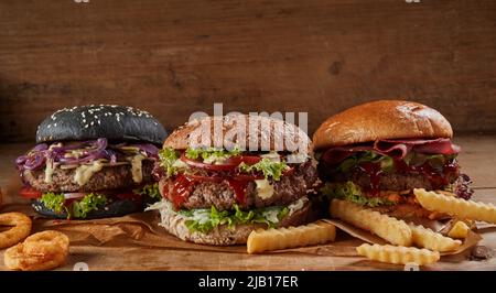 Hamburgers délicieux avec des côtelettes et des légumes placés sur une table en bois avec des frites Banque D'Images