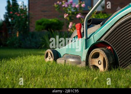 Motionnaire de pelouse sur l'herbe verte dans la maison en brique et en avant Banque D'Images