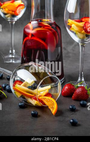 Verre de Sangria rouge et fruits sur table en pierre sombre Banque D'Images