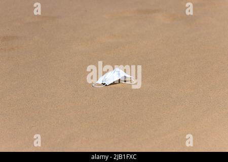 Abandonné un masque jetable dans le sable. Concept de solitude, d'anxiété et de santé mentale de la distanciation sociale dans la crise du coronavirus COVID-19. Banque D'Images