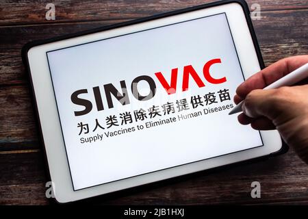 Kumamoto, JAPON - juillet 15 2021 : logo de la société biopharmaceutique chinoise Sinovac Biotech Ltd. Sur tablette avec main et stylo. Concept de vaccin CoronaVac Banque D'Images