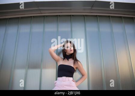 Ensemble de jeunes femmes confiantes en costume élégant regardant l'appareil photo tout en se tenant près d'un mur de verre dans un bâtiment moderne Banque D'Images