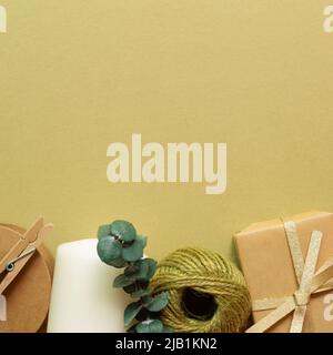 Boîte cadeau marron, rouleau de ficelle, bougie sur fond vert kaki. pose à plat, vue du dessus, espace pour copier Banque D'Images