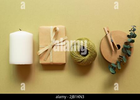 Boîte cadeau marron, rouleau de ficelle, bougie sur fond vert kaki. pose à plat, vue du dessus, espace pour copier Banque D'Images