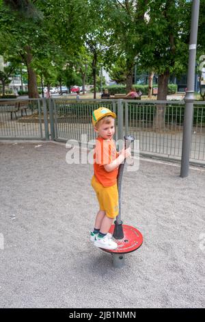 Petit garçon mignon jouant Stand-N-Spin dans le terrain de jeu Banque D'Images