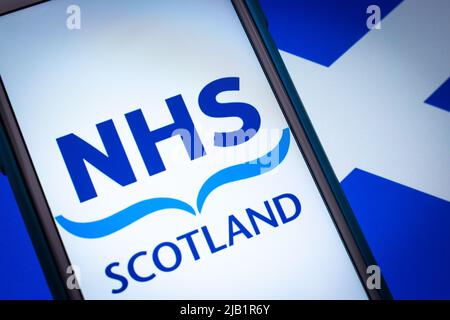 Kumamoto, JAPON - septembre 6 2021 : logo Closeup NHS Scotland, le système de santé financé par l'État en Écosse, sur iPhone, drapeau écossais d'humeur sombre. Banque D'Images