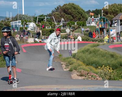 Merville, France, mai 2022. Un homme en Jean et un chapeau rouge fait un skateboard sur la piste du parc. Journée ensoleillée, détente, style de vie sportif Banque D'Images