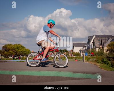 Merville, France, mai 2022. Homme avec un casque à vélo BMX dans le parc de skate. Journée ensoleillée, détente, style de vie sportif Banque D'Images