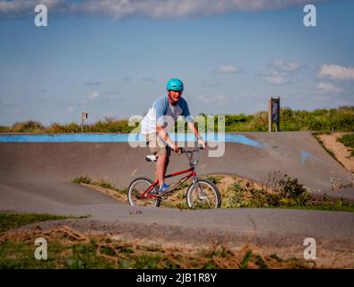 Merville, France, mai 2022. Homme avec un casque à vélo BMX dans le parc de skate. Journée ensoleillée, détente, style de vie sportif Banque D'Images