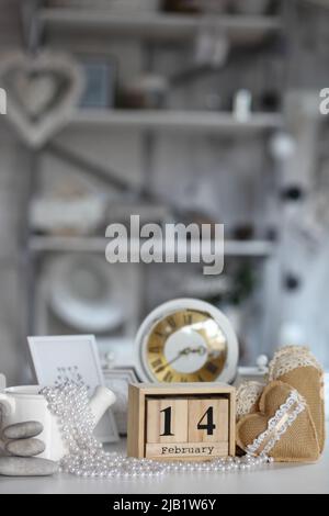 St Valentin concept de la Saint Valentin. Coeur à côté de bloc de calendrier en bois fixé à la Saint Valentin date du 14 février avec horloge blanche sur table et salle lumineuse arrière Banque D'Images