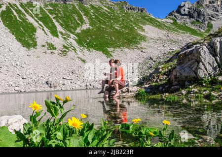 Couple bénéficiant du soleil du matin tout en s'asseyant au Koblatsee près de la Nebelhorn dans les Alpes d'Allgäu Banque D'Images