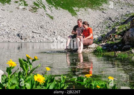 Couple bénéficiant du soleil du matin tout en s'asseyant au Koblatsee près de la Nebelhorn dans les Alpes d'Allgäu Banque D'Images