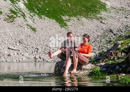 Couple bénéficiant du soleil du matin tout en s'asseyant au Koblatsee près de la Nebelhorn dans les Alpes d'Allgäu Banque D'Images