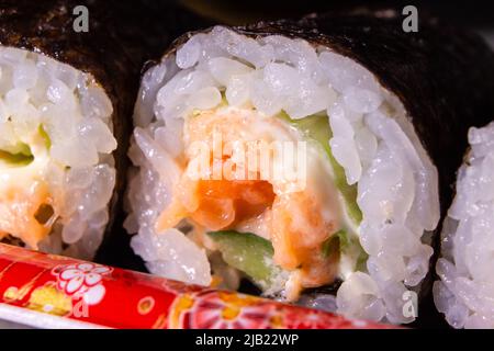 Le gros plan du maki zushi de saumon à emporter (petits pains à sushi au saumon) emballé dans le contenant en plastique. Banque D'Images