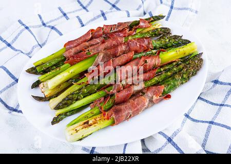 Asperges cuites au four avec bacon et herbes sur fond de bois Banque D'Images