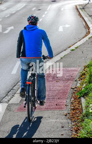 Cycliste passant de la trajectoire de cycle à une route de cyclisme et un sentier de randonnée combinés Banque D'Images