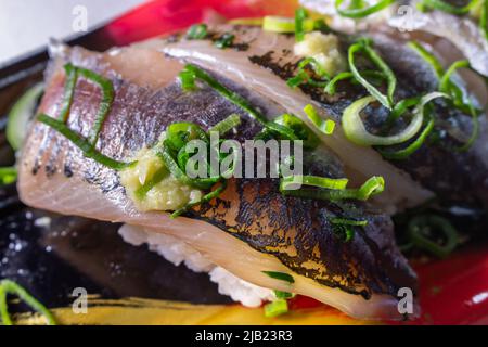 Sushi de maquereau (Aji Sushi) aux oignons verts et gingembre râpé emballés dans un plateau de cuisine. L'Aji est l'un des sushis populaires de type Edomae Banque D'Images