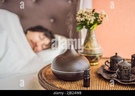 Concept d'aromathérapie. Diffuseur et humidificateur d'huile essentielle à ultrasons en bois électrique. Diffuseur d'arôme ultrasonique pour la maison. Homme reposant à la maison Banque D'Images