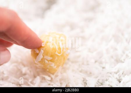 Faire cuire la pâte avec une cuillère à pâte et, après avoir fait rouler les flocons de noix de coco pour cuire les biscuits à la noix de coco. Banque D'Images