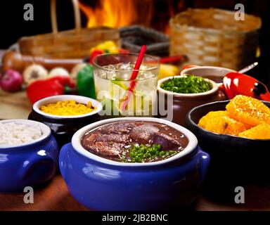 La cuisine brésilienne traditionnelle appelée feijoada. Haricots noirs avec porc, avec caipirinha, chou et orange Banque D'Images
