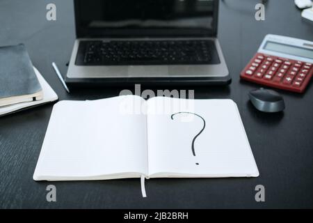 Point d'interrogation dans un bloc-notes sur l'arrière-plan d'un ordinateur portable et d'une calculatrice Banque D'Images