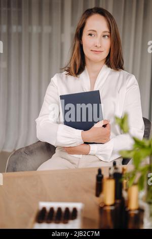 portrait d'une jeune fille souriante assise dans un fauteuil. Un aromathérapeute dans un chemisier blanc est assis dans le bureau. Banque D'Images